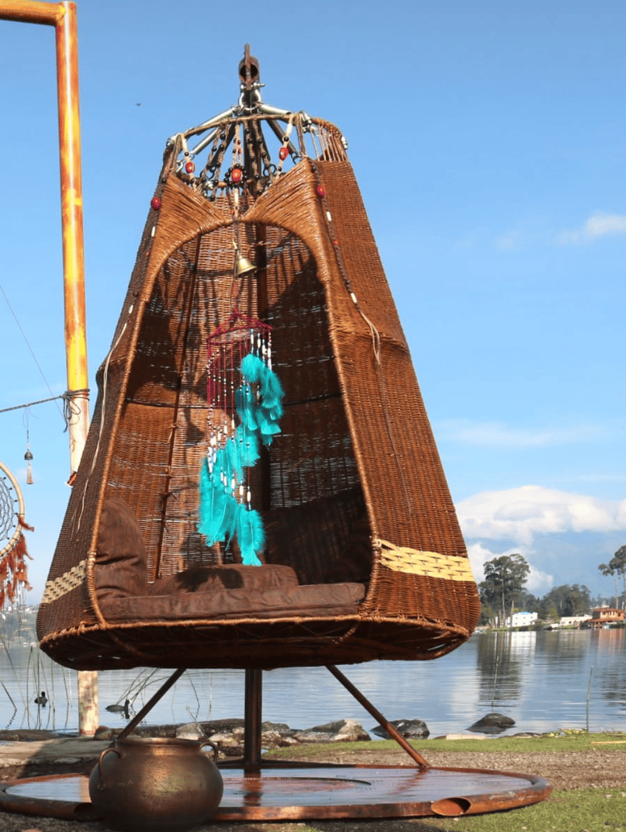 Mecedora de mimbre con atrapasueños turquesa frente al lago