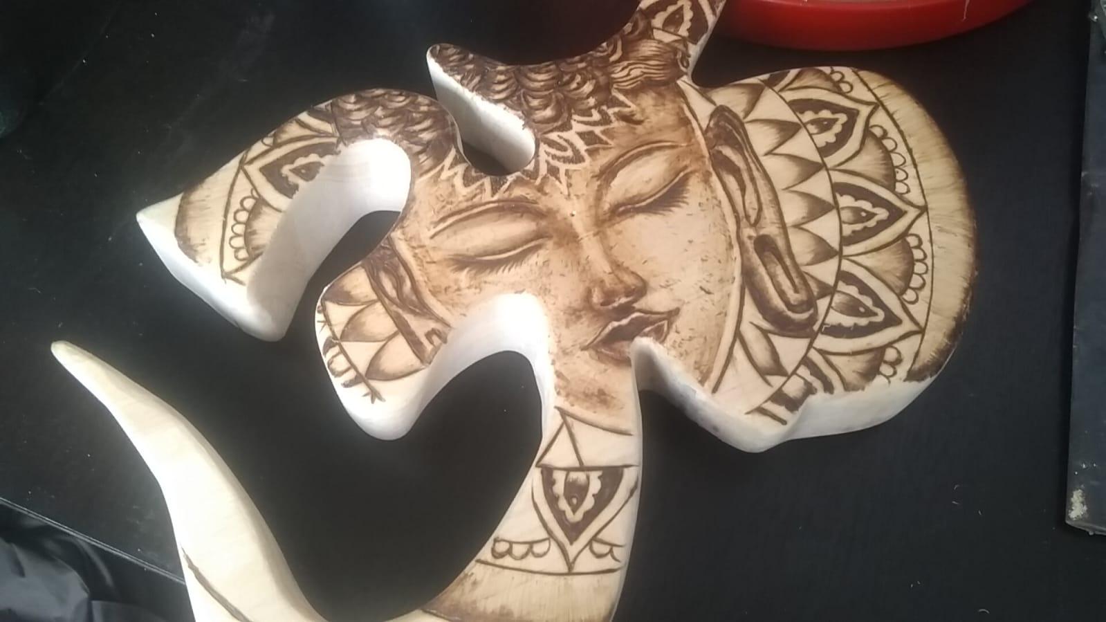 Pirograbado en madera del símbolo Om con rostro de Buda